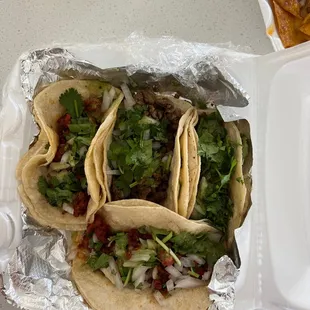 a couple of tacos in a styrofoam container