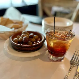 a glass of iced tea and a bowl of olives