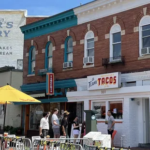 a group of people standing in front of a taco shop