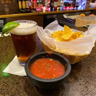 a glass of beer and a bowl of chips