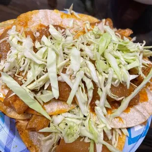 Chicharron in red sauce tacos topped with cabbage and onion