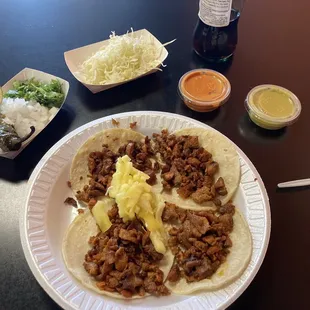 Tacos al pastor.  They have a side bar with onions, cabbage, cilantro, roasted jalapeños, limes, and two different sauces.