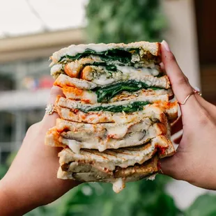 a person holding a stack of sandwiches