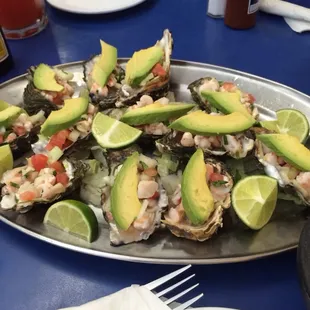 a platter of oysters with avocado and tomatoes