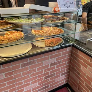 a pizza counter with a variety of pizzas