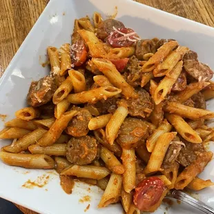 a plate of pasta with meat and tomatoes