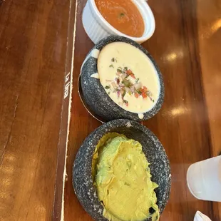 two bowls of guacamole and a bowl of salsa