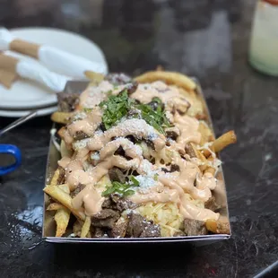 a plate of french fries covered in mushroom sauce