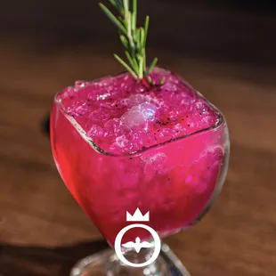 a pink cocktail with a sprig of rosemary