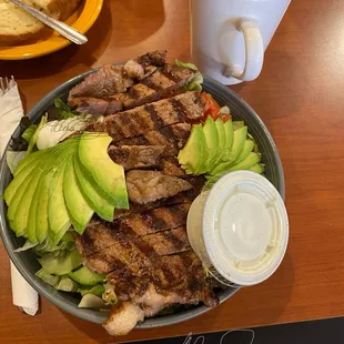 Carne Asada salad with avocado added, side of ranch dressing.