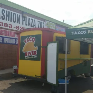 Tiny little trailer in a parking lot in front of a jewelry store.