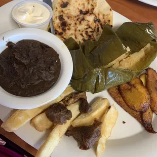 Corn tamale, plantains, yuca, beans, crema, pupusa, and fried pork