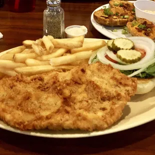 Pork tenderloin with french fries, potato skins appetizer in background