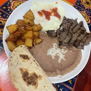 Bistek con huevos, papas y frijoles.