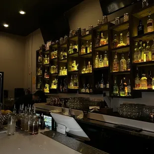 a bar with a counter and shelves of liquor bottles