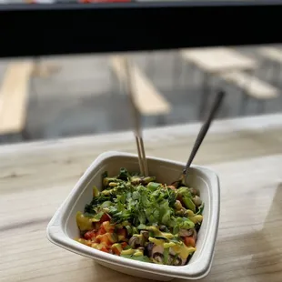 a bowl of salad with chopsticks