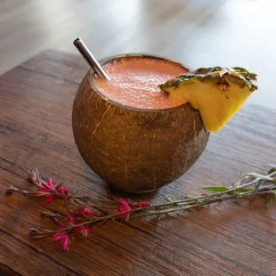 a drink in a coconut bowl with a pineapple garnish