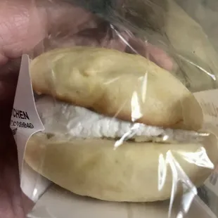 a person holding a sandwich wrapped in plastic