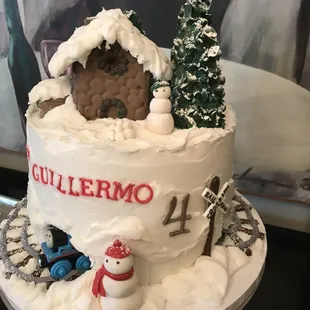 a cake decorated with a house and snowmen