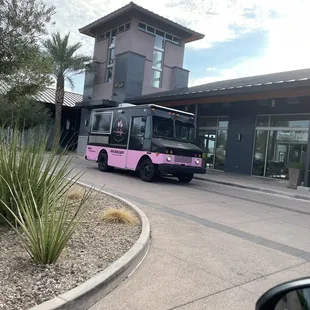 a pink bus parked in front of a building