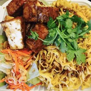 a plate of noodles, meat, and vegetables