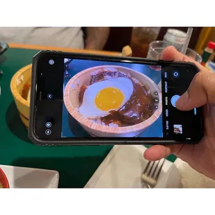 a person taking a picture of a bowl of food