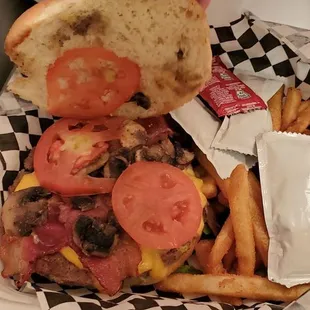 a hand holding a sandwich and french fries