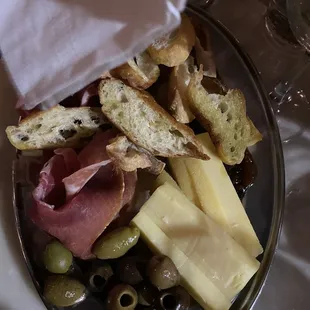 a plate of cheese, olives, and bread