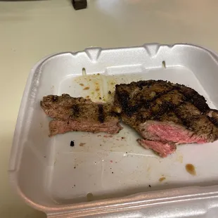 a steak in a styrofoam container