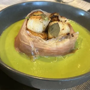 Scallops wrapped in prosciutto in a pea puree