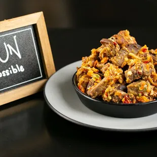 Indulge in Asun: diced goat meat cooked with assorted peppers, bursting with flavor and spice. A popular, fiery street food favorite