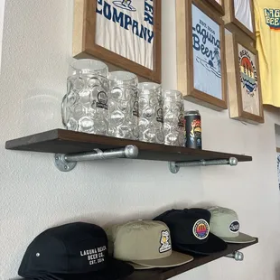 a shelf of beer glasses and hats