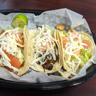 Carnitas, steak, chicken tacos with lettuce, cheese, and tomatoes
