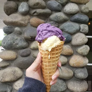 Ube ice cream on top, lilikoi (passion fruit) on bottom in a waffle cone.