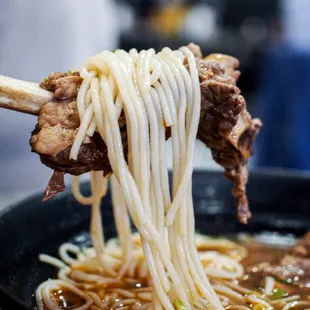 chopsticks lifting noodles from a bowl