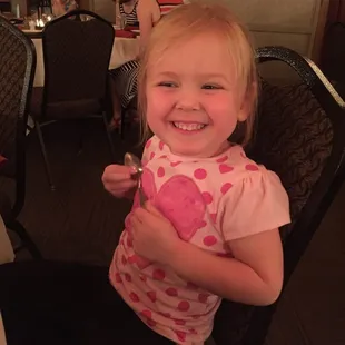 a little girl sitting in a chair and smiling
