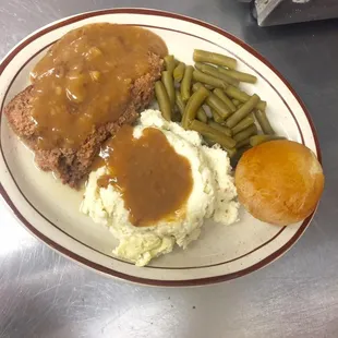 a plate of meatloaf, mashed potatoes and green beans