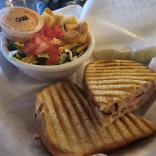 Ham and cheese panini sandwich on sourdough, and a side salad.
