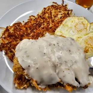 a plate of food with hash browns, eggs, and gravy