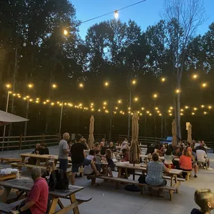 people sitting at picnic tables under string lights