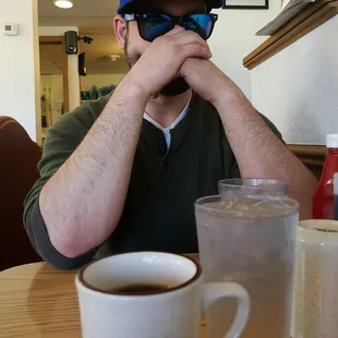 a man sitting at a table with a cup of coffee