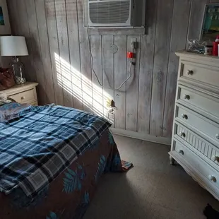 a bedroom with a bed, dresser, and air conditioner