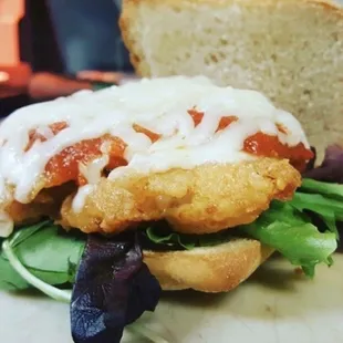 a fish sandwich with lettuce and tomato sauce