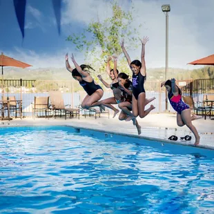 a group of girls jumping into a swimming pool