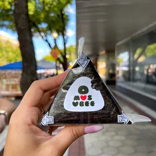a hand holding a triangle shaped bag of seaweed