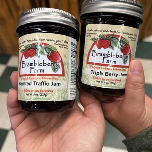 a hand holding two jars of jam
