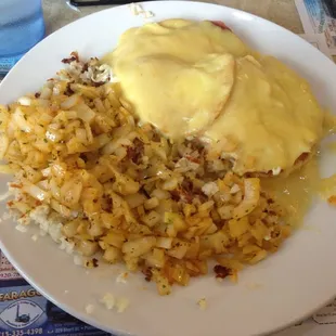 Eggs Benedict and hash browns with grilled onions.