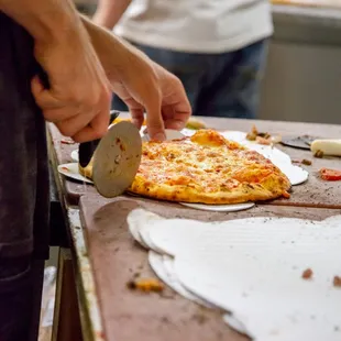 a person cutting a pizza