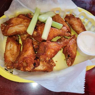 a basket of chicken wings with celery and ranch dressing
