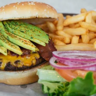 a cheeseburger with avocado and fries